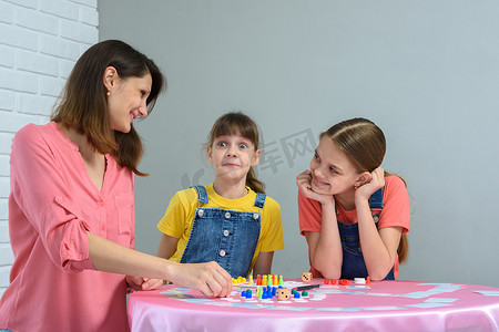 女孩和妈妈和姐姐一起玩棋盘游戏，做了一张滑稽的脸