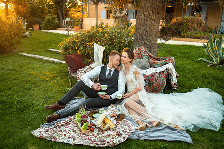 日落时分，新婚夫妇在草坪上共进晚餐。法国日落时分，一对夫妇坐着喝茶