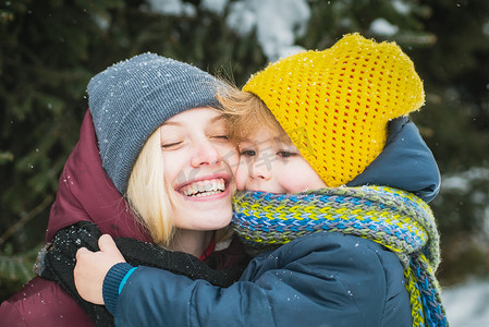 年轻的母亲带着可爱的孩子在冬天下雪的公园。