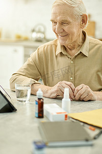 令人高兴的老人带着医疗用品坐在桌旁