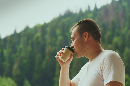 愉快的人花时间享受假期和在山林背景下喝咖啡的肖像。