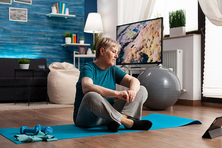 高级女性坐在瑜伽垫上的莲花位置训练身体肌肉减肥