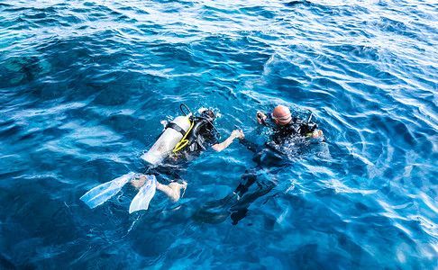 潜水教练在蔚蓝的海水中牵着弟子的手