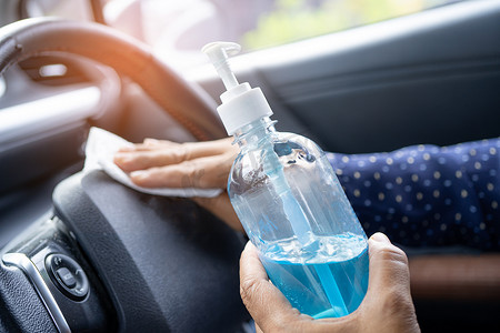 新常态，亚洲职业女性用蓝色酒精消毒凝胶清洁车内，以保护冠状病毒的安全。