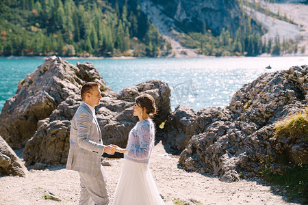 白云站摄影照片_新娘和新郎站在石头背景下，俯瞰意大利的布拉伊埃斯湖。