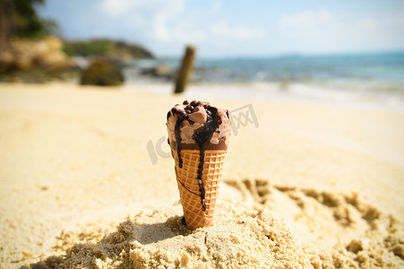 沙滩背景摄影照片_沙滩背景上的冰淇淋锥-b 上融化的冰淇淋
