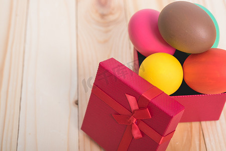 蓝色礼物摄影照片_复活节彩蛋在木制背景的红盒礼物中干净