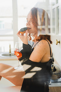 酒红色头发摄影照片_女孩坐着吃蛋糕，喝着酒。