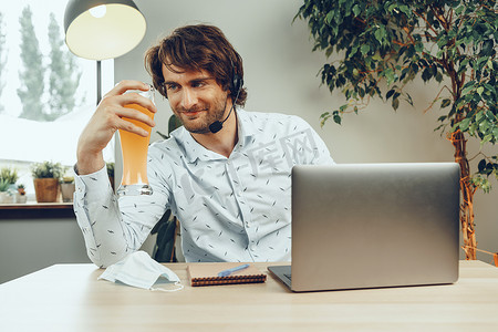留着胡子的男人一边喝啤酒一边使用笔记本电脑