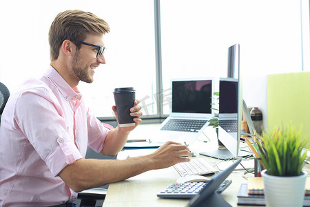 穿着衬衫、体贴的年轻商人坐在办公室里使用电脑工作。