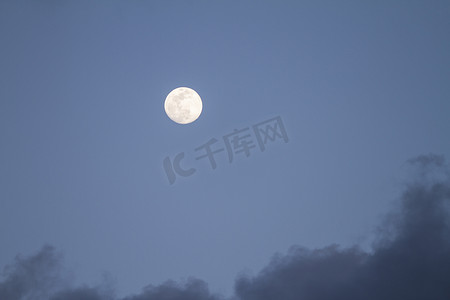 山水灰色摄影照片_满月在深蓝色的天空中升起，有些灰色的云