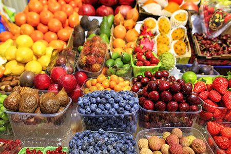 草莓牛油果摄影照片_蓝莓、蛇果、樱桃、酸橙、石榴、草莓、李子、柠檬、鳄梨、芒果在市场上出售。