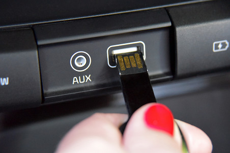 女性手指将 USB 存储器插入汽车仪表板上的 usb 端口