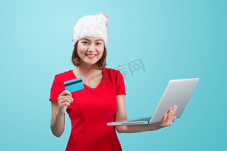 冬季亚洲女性拿着笔记本电脑和信用卡反对蓝色小插图