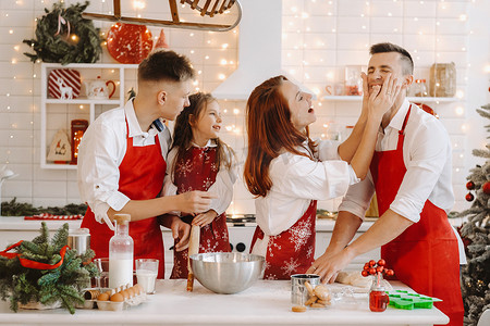 一个幸福的家庭站在圣诞厨房里，互相抹面粉