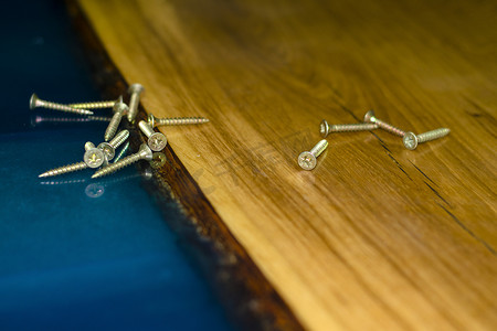 环氧树脂摄影照片_桌子上的金螺丝由木头和环氧树脂制成