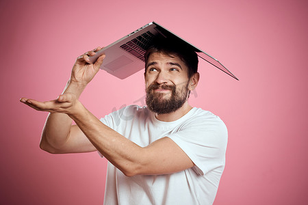 开朗的男人，头上戴着一台打开的笔记本电脑，粉色背景裁剪视图复制空间