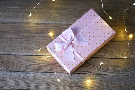 粉色礼品盒摄影照片_粉色礼品盒花环装饰木质背景节日