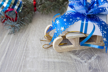 木制雪橇上放着一份带有蓝色大蝴蝶结的圣诞礼物。