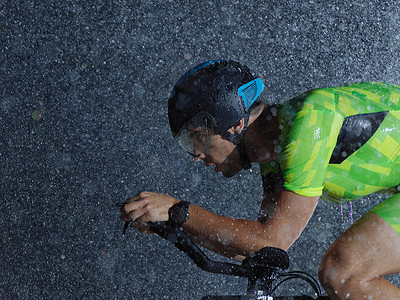 雨循环摄影照片_铁人三项运动员在雨夜骑自行车