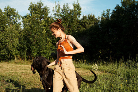 宠物家庭摄影照片_在户外田野里与狗友谊玩耍的女人