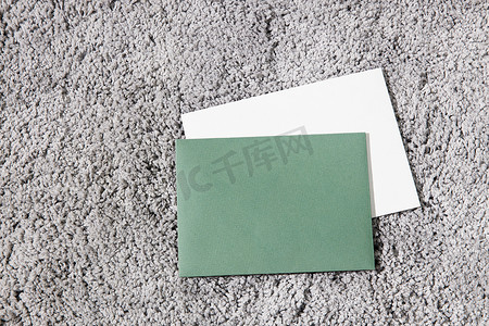 绿色和白色的信封位于灰色蓬松的表面上。