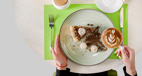 一块巧克力蛋糕，上面装饰着蛋白酥皮、咖啡豆和饼干屑，手里拿着一杯卡布奇诺。