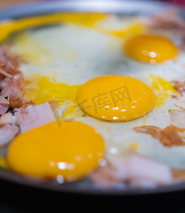 圆火腿摄影照片_将切碎的火鸡火腿和三个蛋黄放在圆煎锅上