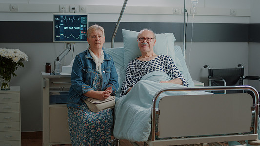 医院病床上接受妻子协助的老人肖像