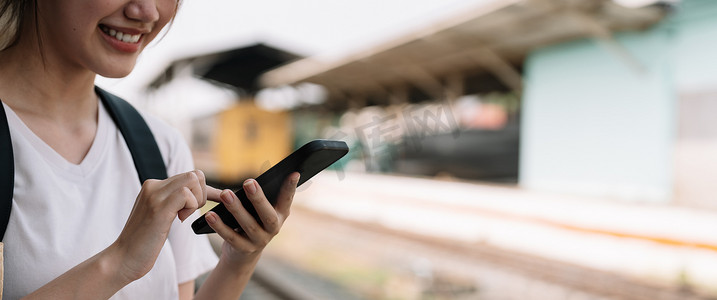 在火车站夏季旅游概念中使用智能手机的女性特写手