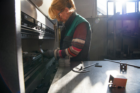 在现代化工厂工作并为数控机床准备材料的妇女。