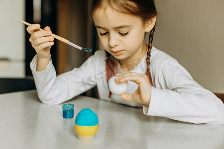 可爱的小女孩画着蓝色和黄色的复活节彩蛋。