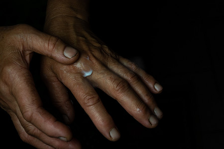 液位摄影照片_一位老妇人将护手霜擦到有皱纹的皮肤上。