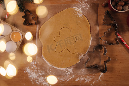 康乃馨手工摄影照片_用于在木桌上烹饪圣诞饼干姜人的生面团的顶部视图。