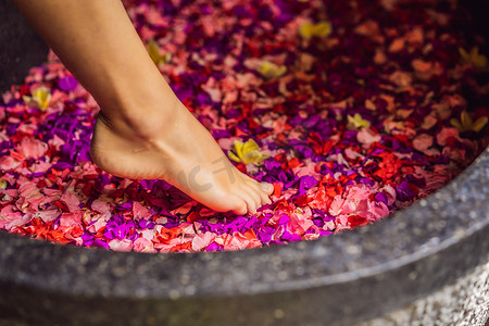 花瓣摄影照片_有魅力的年轻女子在沐浴着热带花卉和芳香油的花瓣。