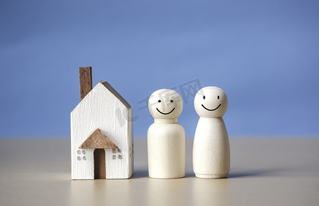 背景人物蓝色摄影照片_两个幸福的木制人物和蓝色背景的房子。