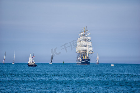 一艘张着白帆的大船在蔚蓝的水面上航行。