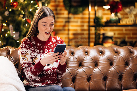 快乐的笑声让白人女性惊讶地看着智能手机屏幕，收到令人难以置信的消息，庆祝赢得新年或圣诞节在线彩票。