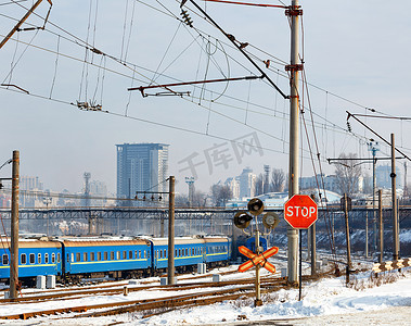 火车站背景摄影照片_铁路道口的红色停车标志以火车站和冬季城市建筑为背景。