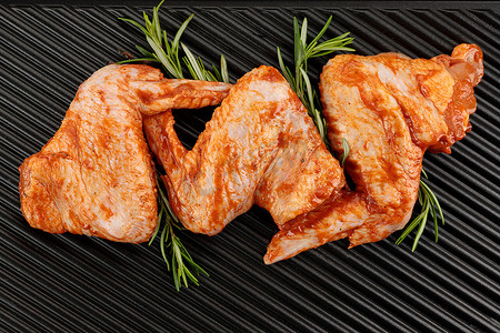 新鲜的生腌制鸡翅放在电烤架上，配上迷迭香。