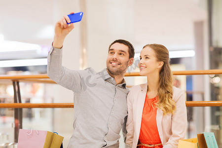 幸福的夫妇用智能手机在商场里自拍