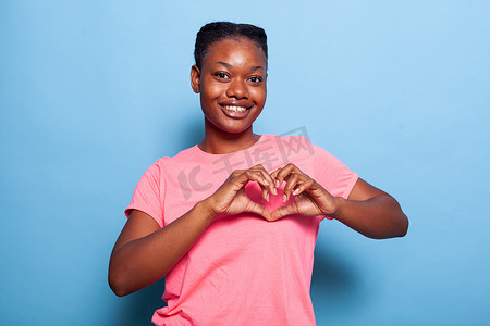 非洲裔美国年轻女性对着镜头微笑的肖像制作心形符号
