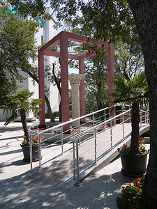 一个不寻常的喷泉，其形式为仿古风格的白色柱子和浅红色瓷砖包围的方形拱门