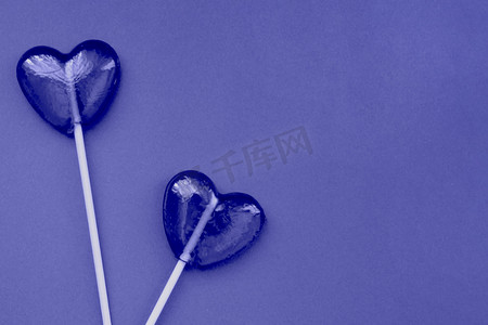 紫色棒棒糖以紫色背景上的心形形式。