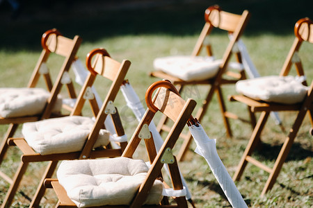 婚礼场地的绿草地上摆放着椅子，椅子上挂着白色的雨伞