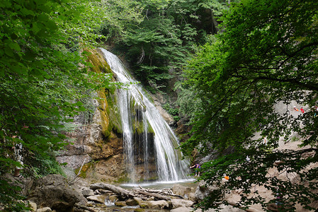 瀑布水流摄影照片_美丽的瀑布，清澈的水流着森林里的石头