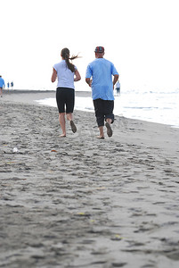 海滩奔跑的美摄影照片_海滩上奔跑的情侣