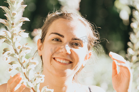 一位微笑的年轻女子靠近鲜花的肖像、心理健康和自我护理概念、心理学、年轻人