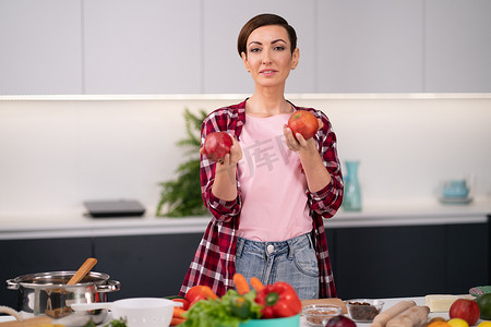 手里拿着水果的女人站在厨房里。