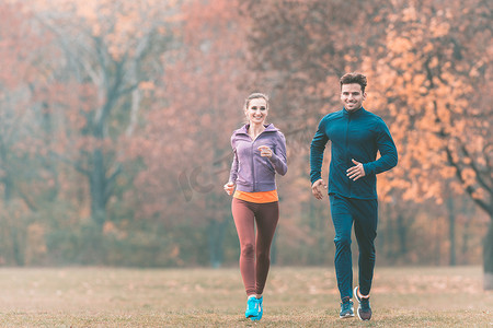 逐步提高摄影照片_情侣在美妙的秋季风景中跑步以提高健身水平